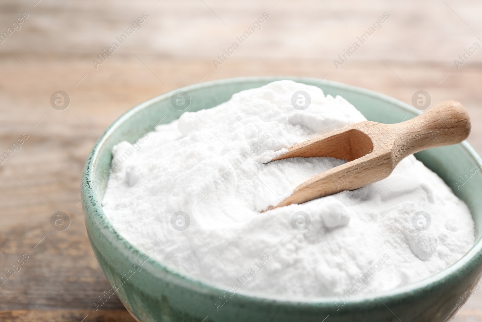 Photo of Bowl with baking soda and scoop on wooden table