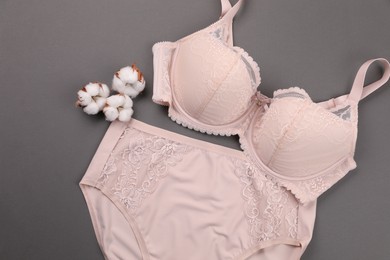 Photo of Elegant beige plus size women's underwear and fluffy cotton flowers on grey background, flat lay