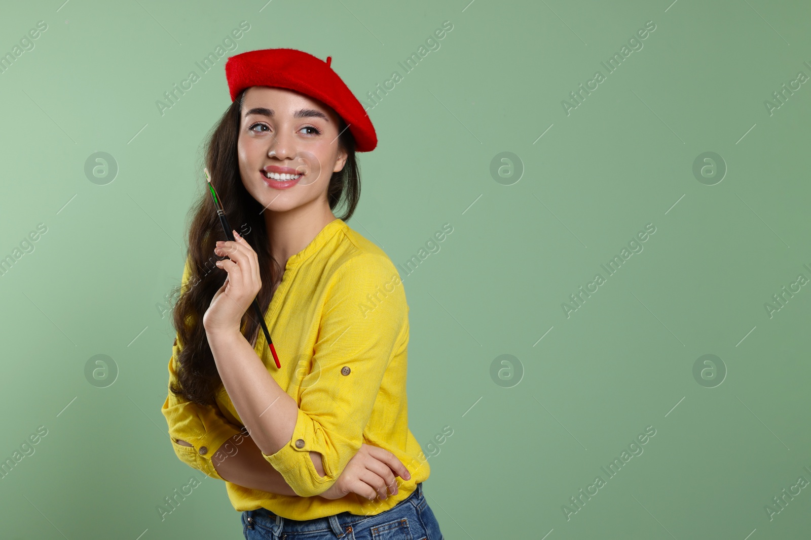 Photo of Woman with paintbrush on pale green background, space for text. Young artist