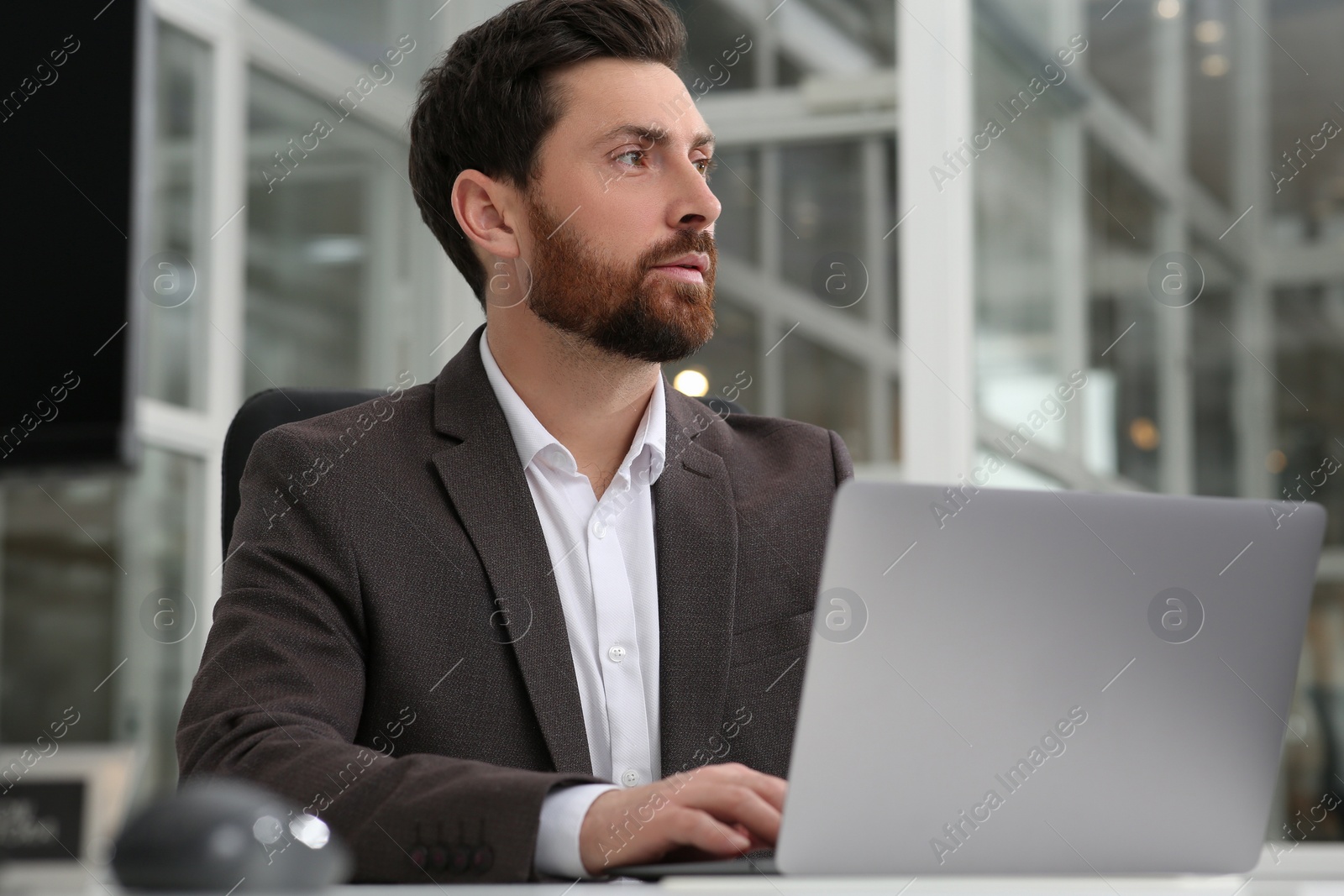 Photo of Man working on laptop at white desk in office