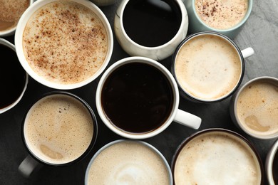 Many cups of different coffees on slate table, flat lay