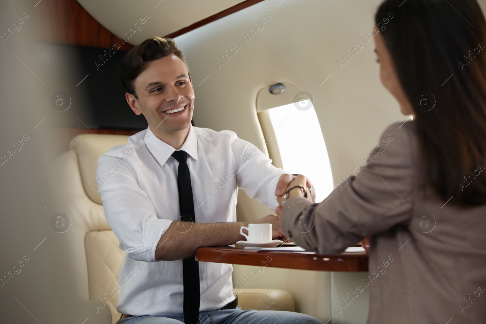 Photo of Colleagues shaking hands in airplane during flight