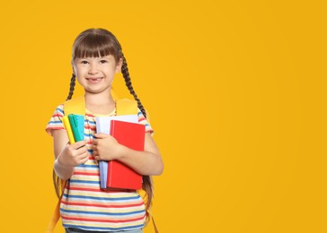 Cute girl with school stationery on yellow background, space for text