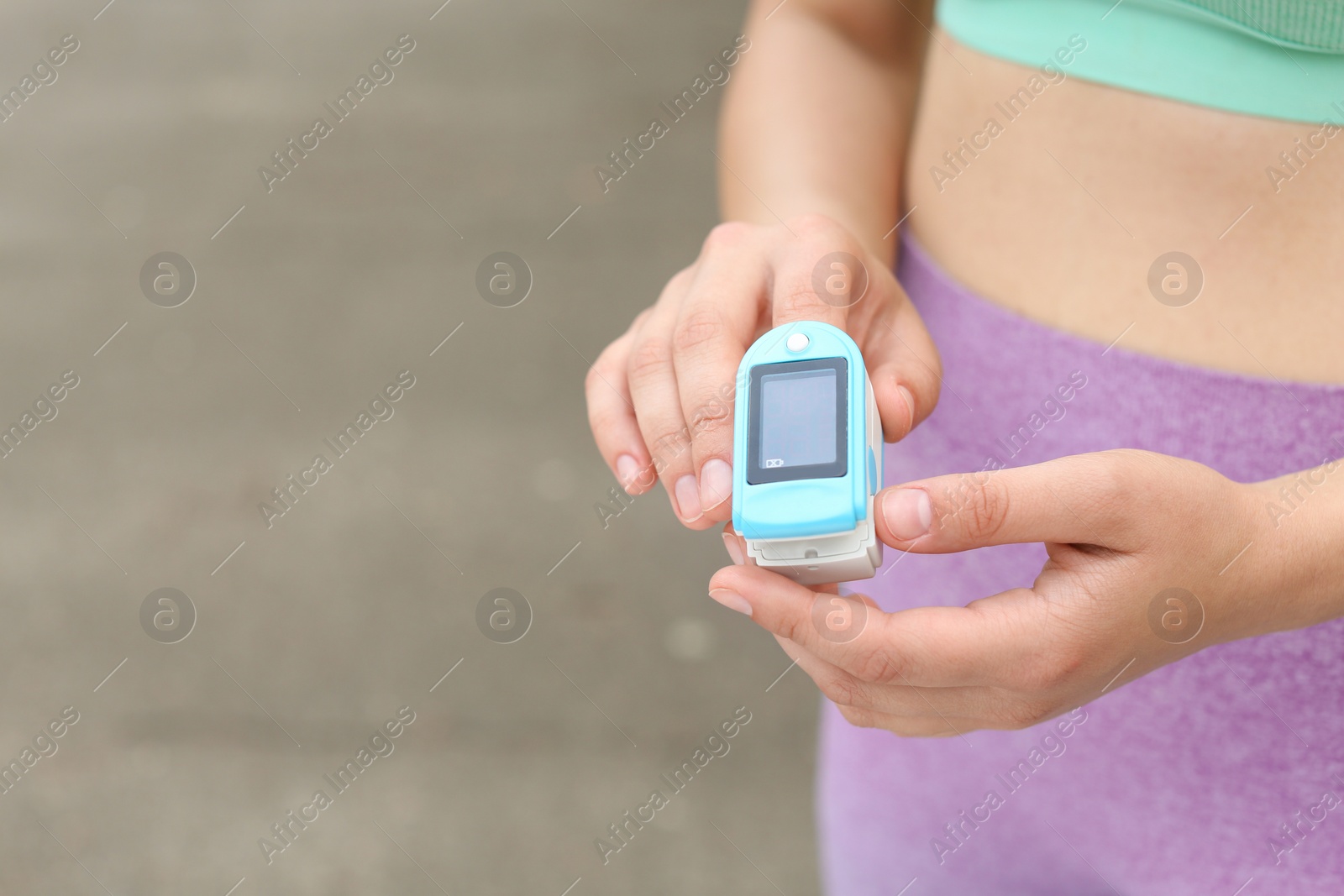 Photo of Young woman checking pulse with medical device after training on street, closeup. Space for text