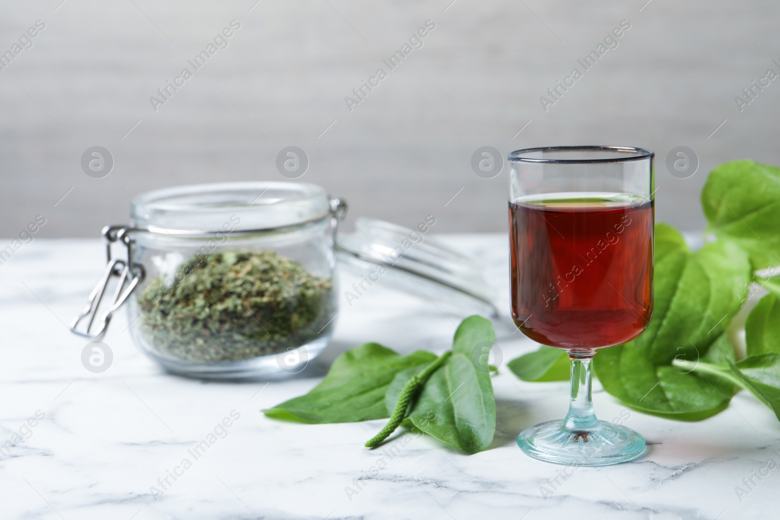 Photo of Broadleaf plantain tincture on white marble table, space for text