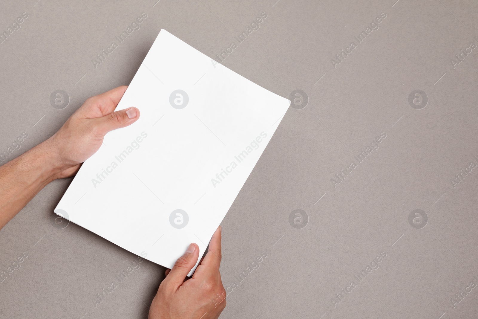 Photo of Man holding sheets of paper on grey background, closeup. Mockup for design