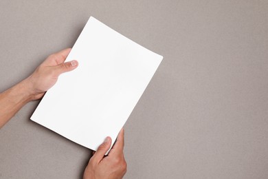 Man holding sheets of paper on grey background, closeup. Mockup for design