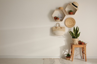 Photo of Room interior with hexagon wooden shelves on light wall. Space for text