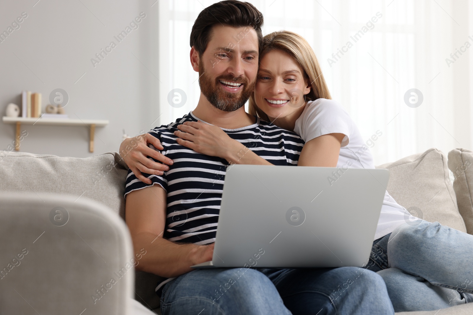 Photo of Happy couple with laptop on sofa at home