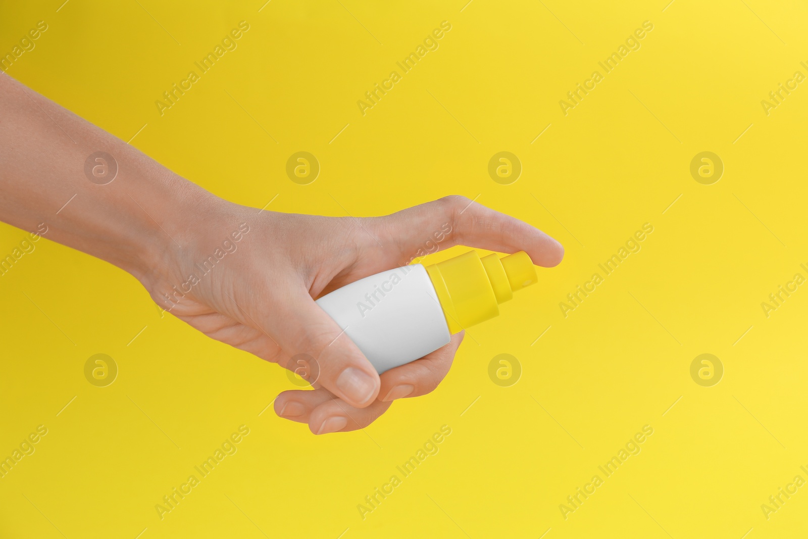 Photo of Woman with bottle of insect repellent spray on yellow background, closeup