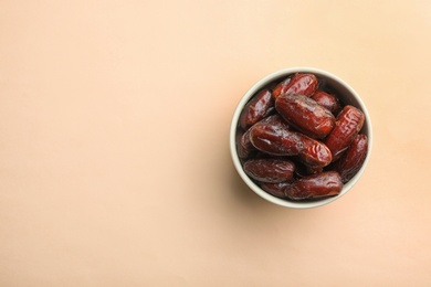 Photo of Bowl with sweet dried date fruits on color background, top view. Space for text