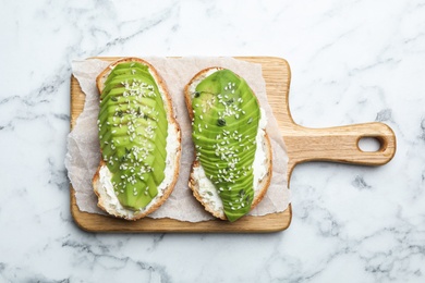 Photo of Tasty avocado sandwiches on white marble table, top view