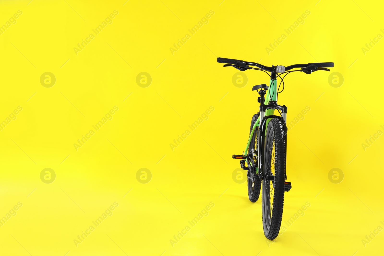 Photo of Modern bicycle on yellow background. Space for text