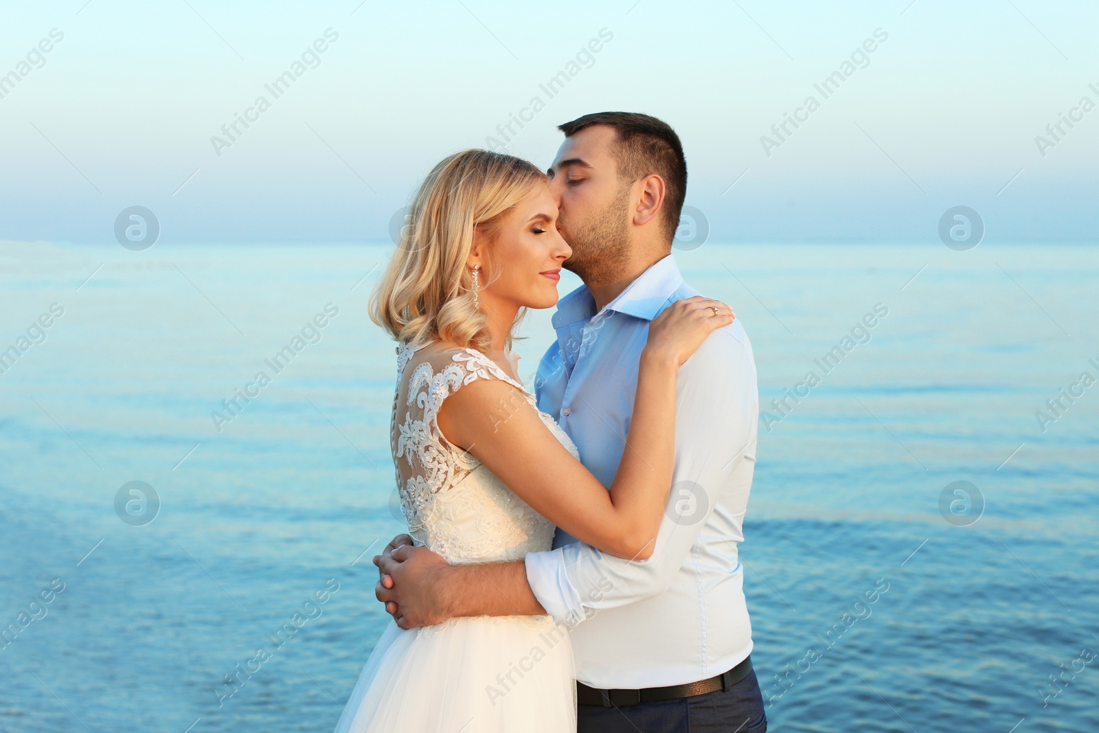 Photo of Wedding couple. Groom kissing bride on beach