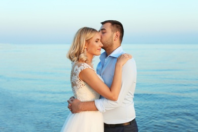 Wedding couple. Groom kissing bride on beach