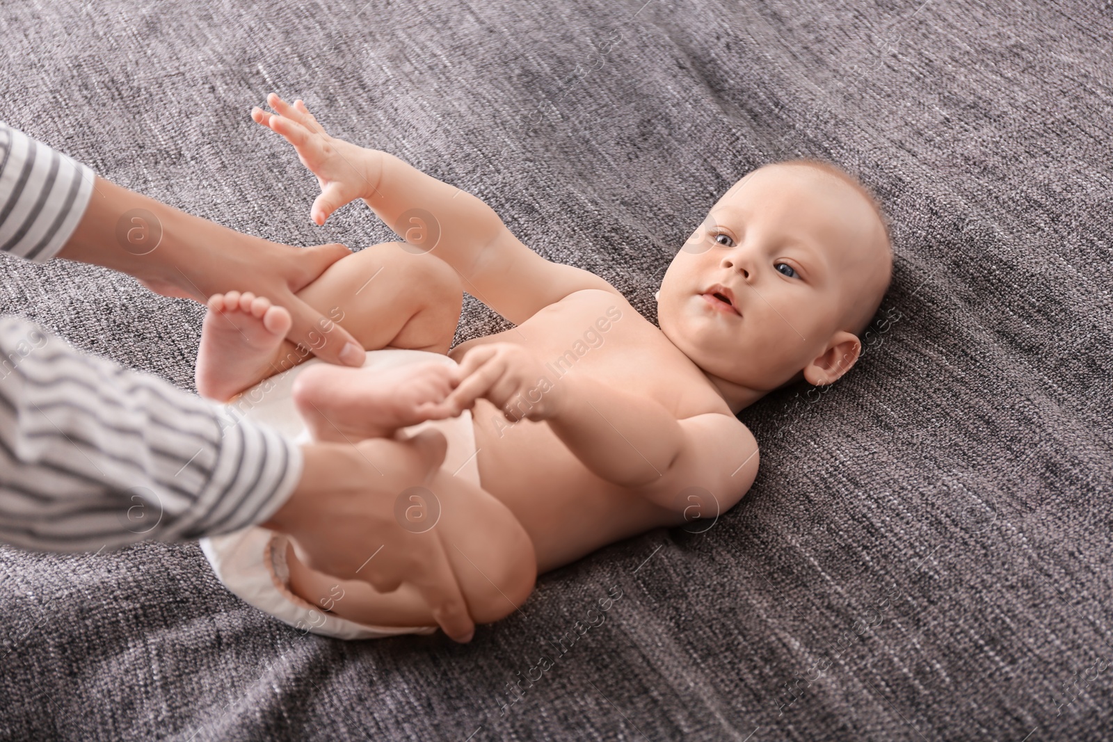 Photo of Young woman massaging cute little baby on blanket