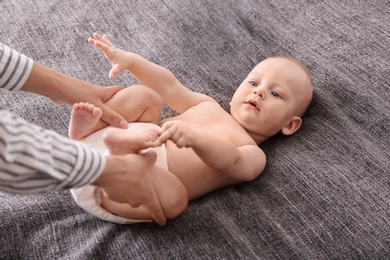 Young woman massaging cute little baby on blanket