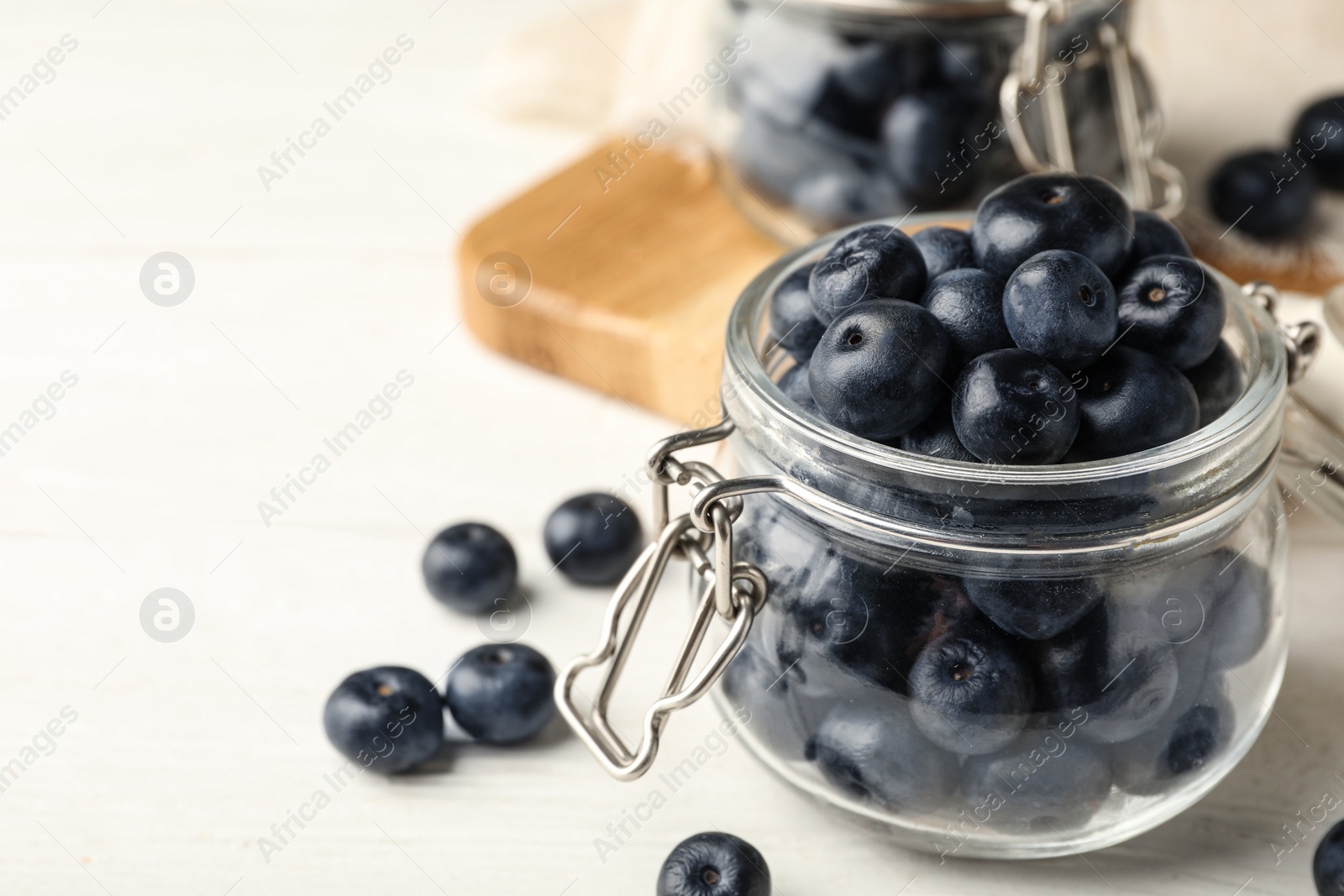 Photo of Jar of fresh acai berries on white wooden table, closeup view. Space for text