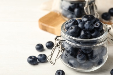 Photo of Jar of fresh acai berries on white wooden table, closeup view. Space for text