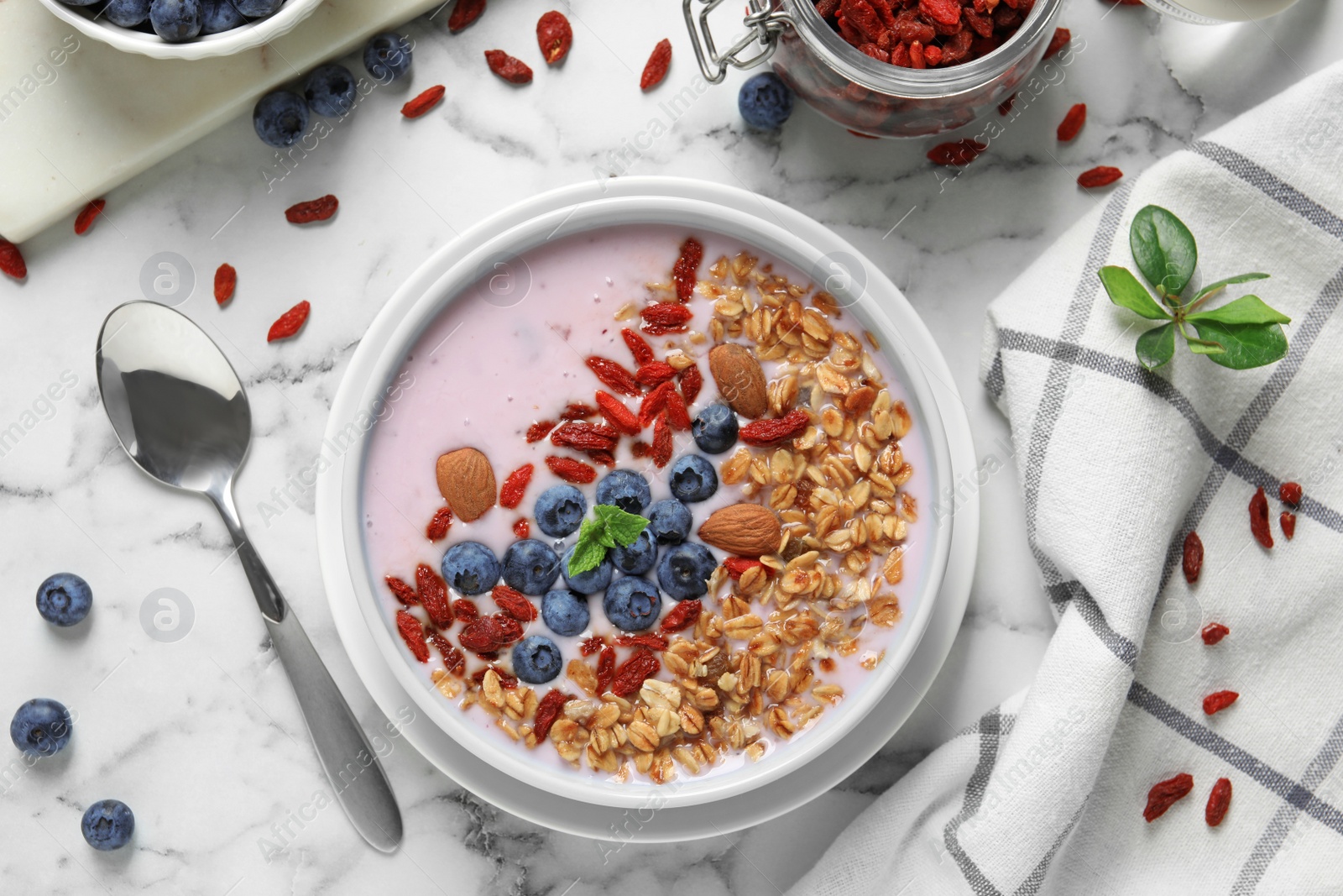 Photo of Flat lay composition of smoothie bowl with goji berries on marble table