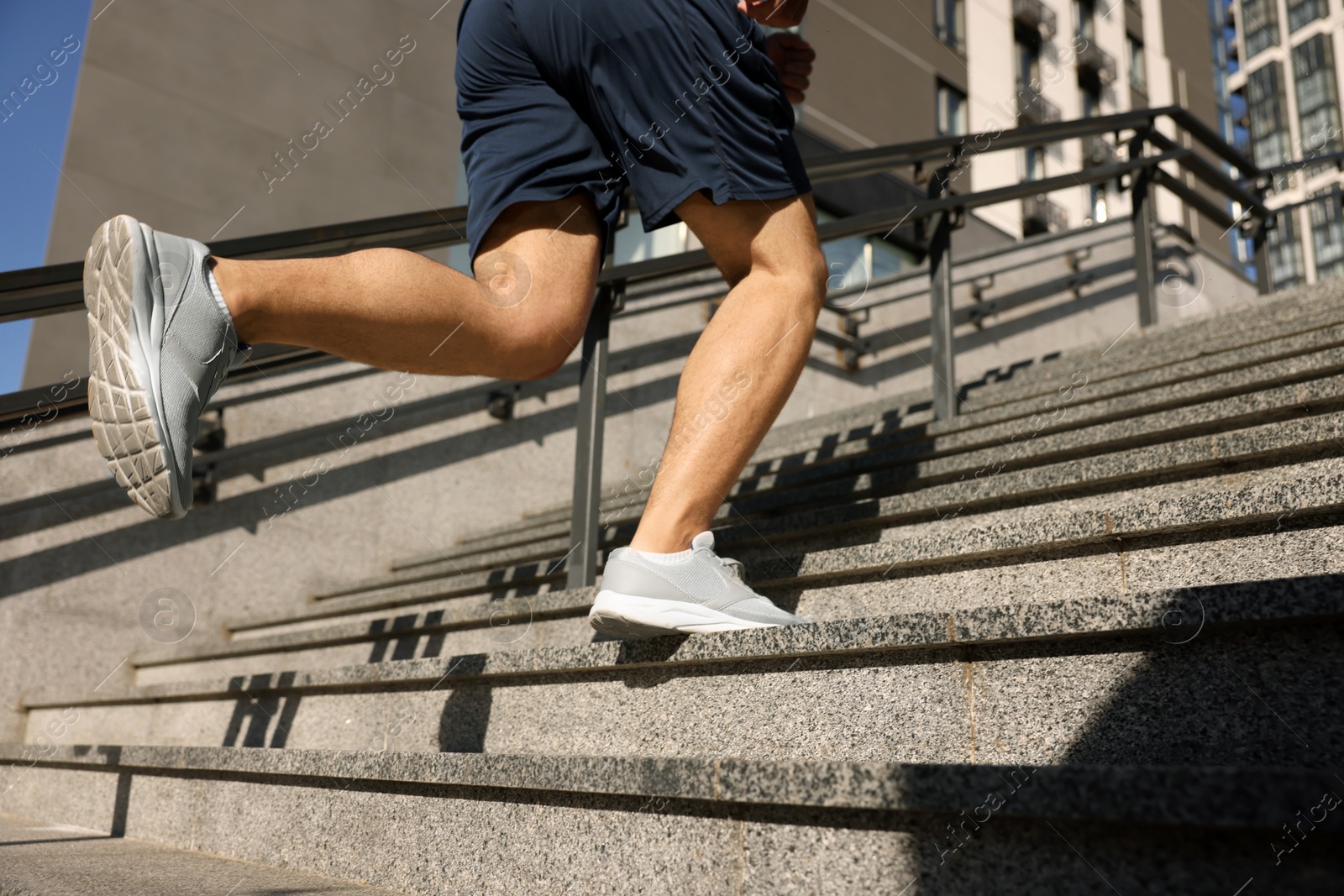 Photo of Man running up stairs outdoors on sunny day, closeup