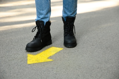 Photo of Person standing near arrow on asphalt, closeup