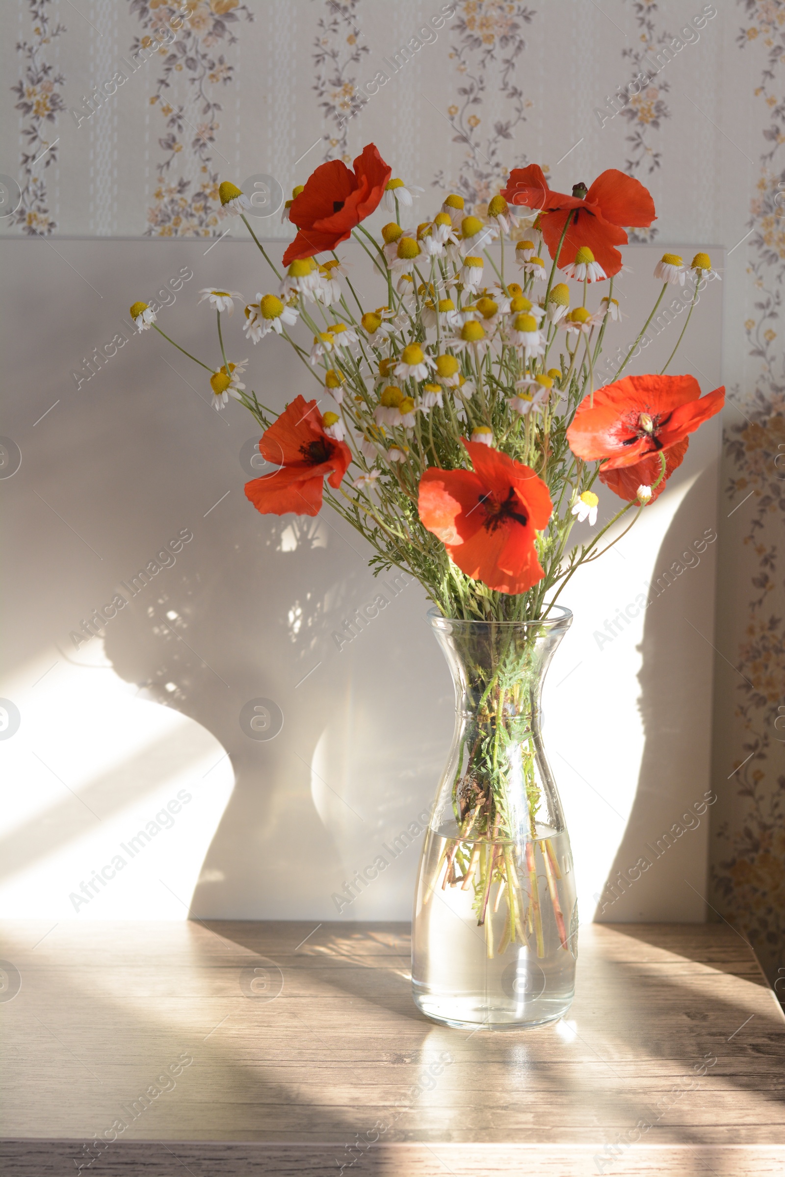 Photo of Bouquet of beautiful wildflowers in glass vase on wooden table indoors