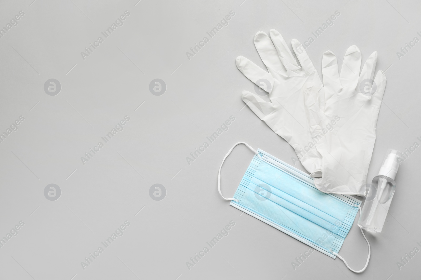 Photo of Medical gloves, protective mask and hand sanitizer on grey background, flat lay. Space for text