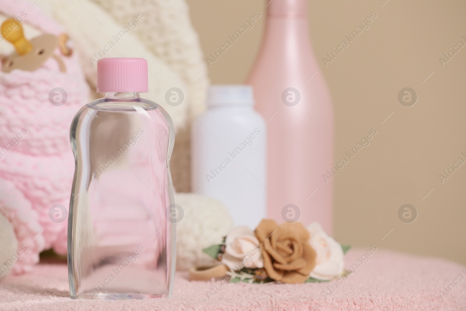 Photo of Baby cosmetic products and accessories on pink towel against beige background. Space for text