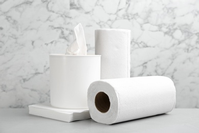 Photo of Clean napkins, box with tissues and rolls of paper towels on light table