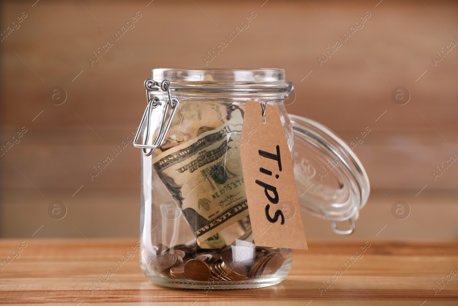 Photo of Glass jar with tips on wooden table, closeup
