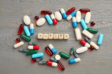 Cubes with word Doping and drugs on light grey wooden background, flat lay