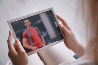 Photo of Woman holding framed photo of happy man indoors, closeup