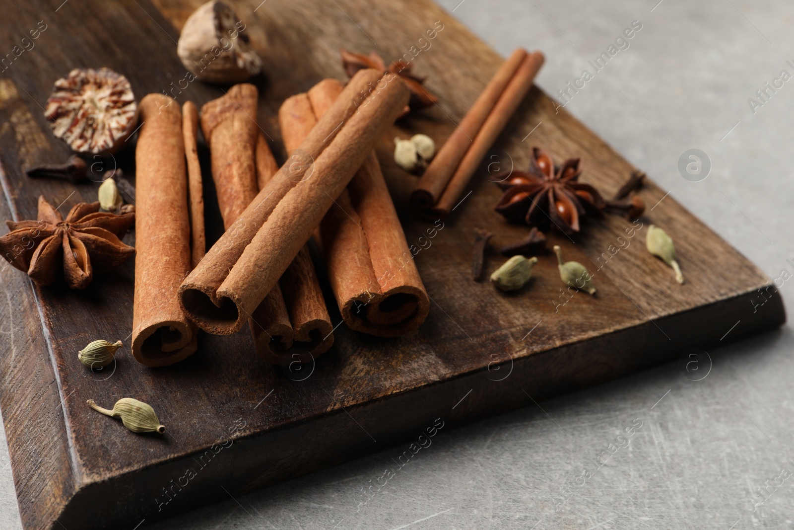 Photo of Board with different aromatic spices on light table, closeup