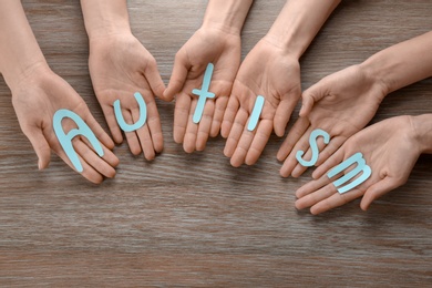 Photo of Group of people holding word "Autism" on wooden background
