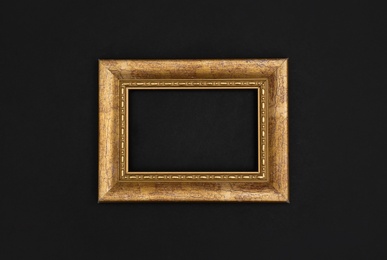 Photo of Gold painted frame on black background, top view with space for text