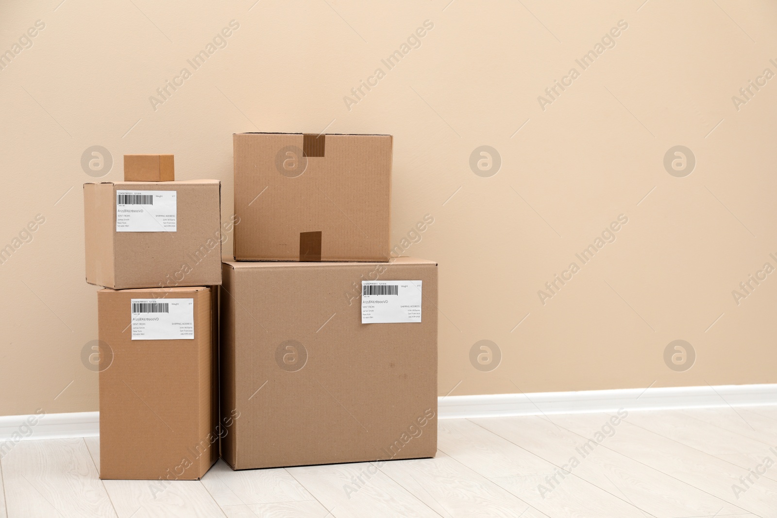 Photo of Stacked parcel boxes on floor against light wall