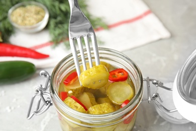 Jar with pickled cucumbers on grey table, closeup view