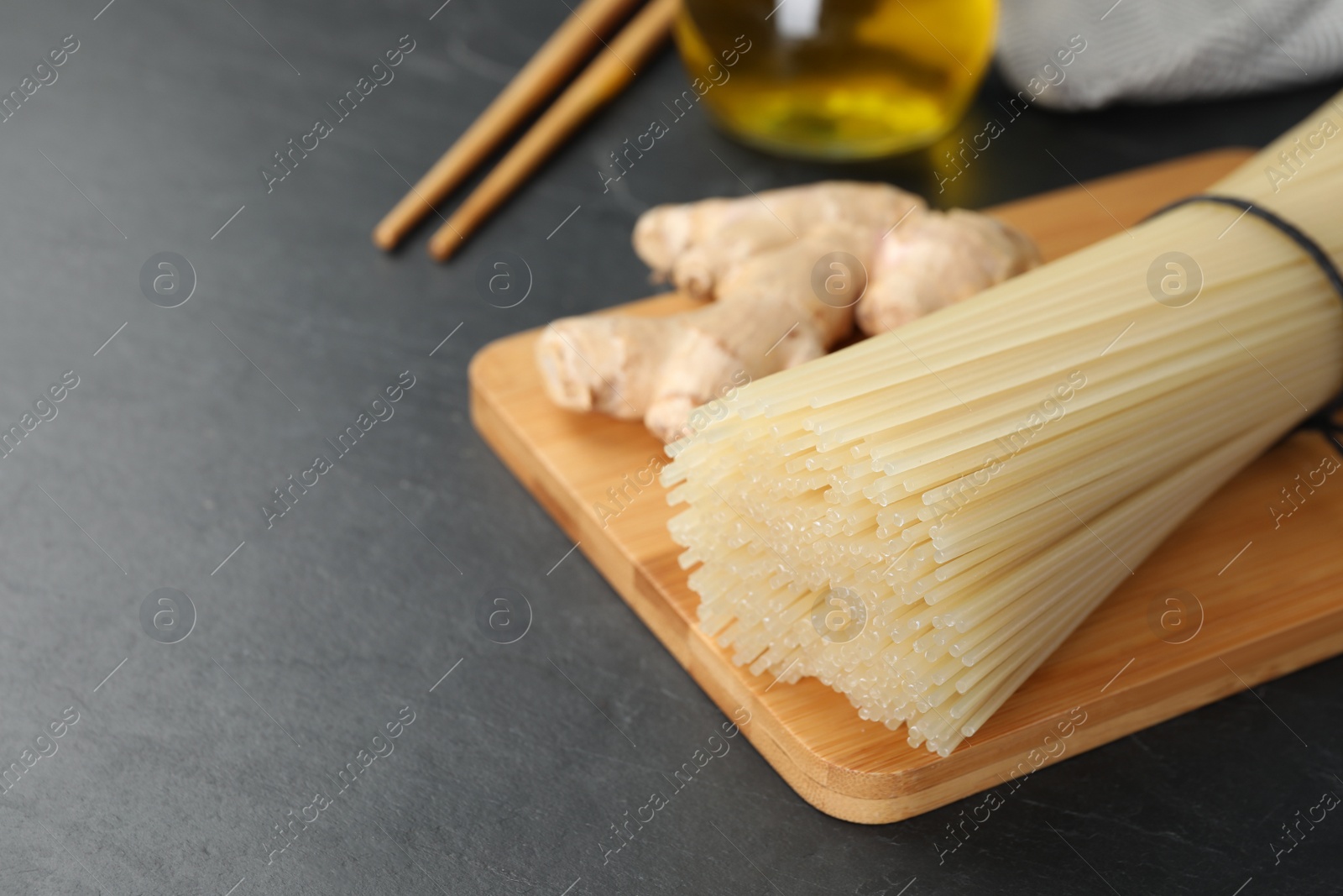 Photo of Dried rice noodles with ginger on black table, closeup. Space for text
