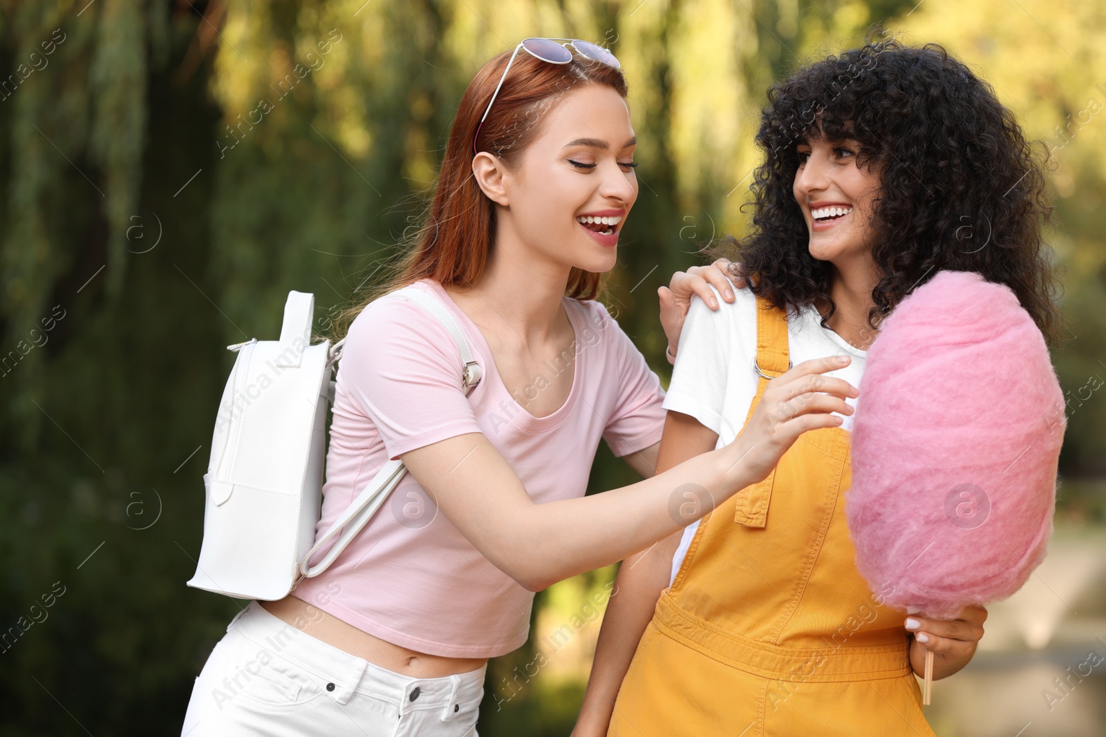 Photo of Happy friends with cotton candies spending time together in park on sunny day