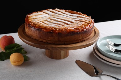 Tasty apricot pie with powdered sugar on table