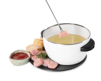 Dipping piece of raw meat into oil in fondue pot on white background