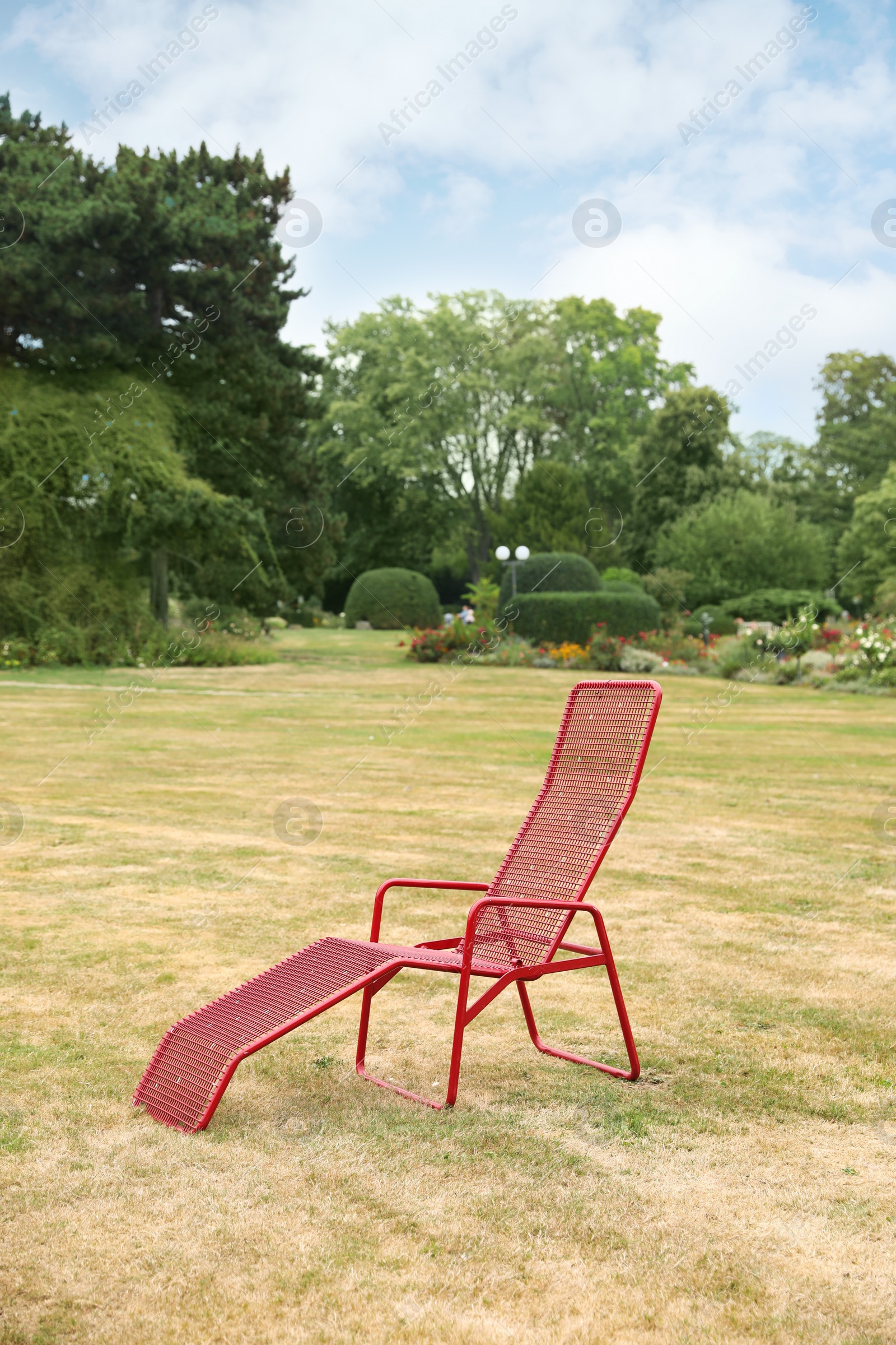 Photo of Red deck chair on green grass in park