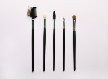 Photo of Different makeup brushes on white background, flat lay