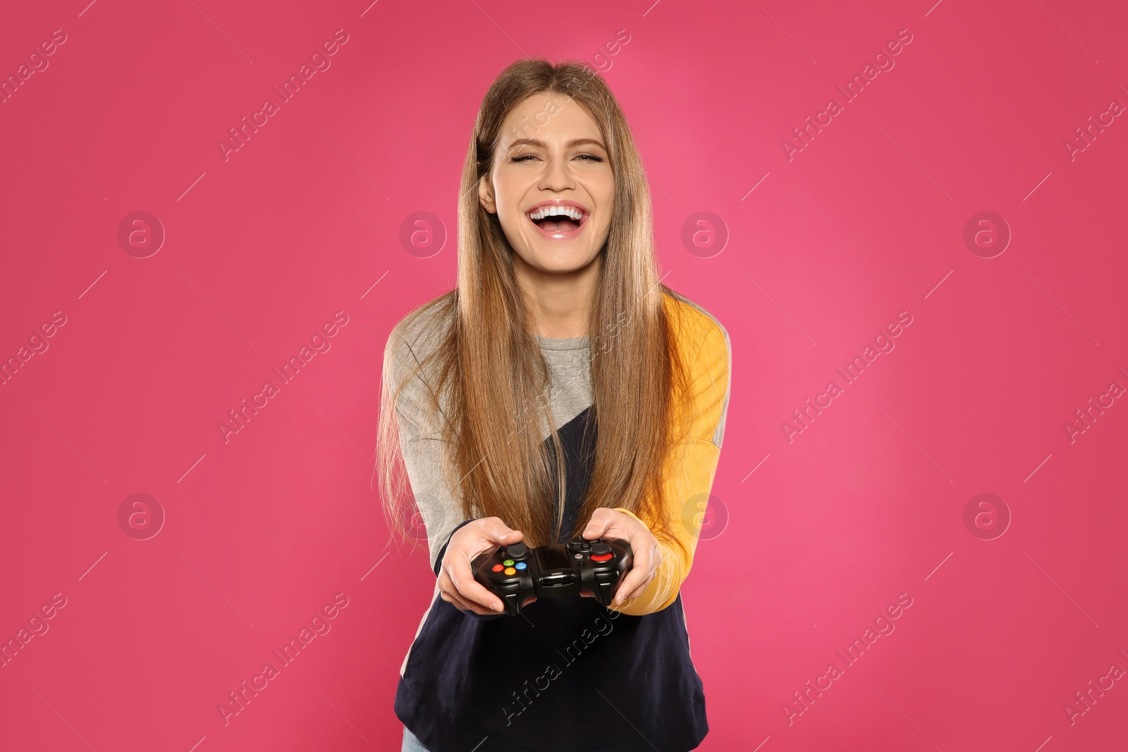 Photo of Emotional young woman playing video games with controller on color background