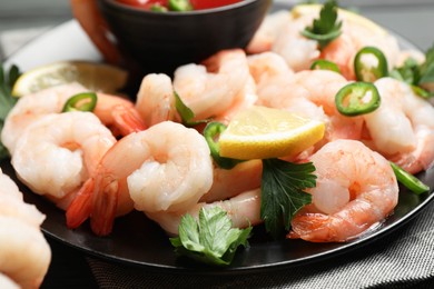 Photo of Tasty boiled shrimps with cocktail sauce, chili, parsley and lemon on table, closeup