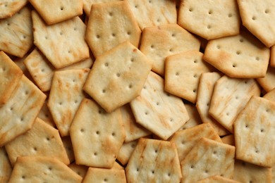 Many delicious crackers as background, top view