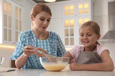 Mother and daughter making dough together in kitchen