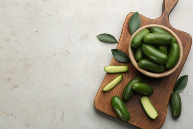 Photo of Wooden bowl and board with seedless avocados on grey table, flat lay. Space for text