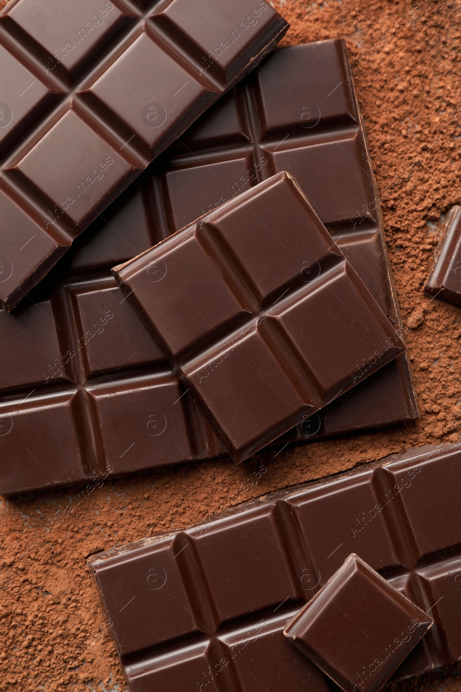 Photo of Delicious dark chocolate and cocoa powder on table, flat lay